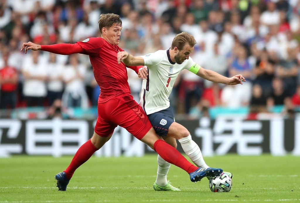 Dänemarks Jannik Vestergaard (l) und Englands Harry Kane kämpfen um den Ball - im Hintergrund eine chinesische Bandenwerbung.