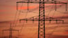 Eine Hochspannungsleitung ist nach Sonnenuntergang vor dem orangerot gefärbten Himmel zu sehen.