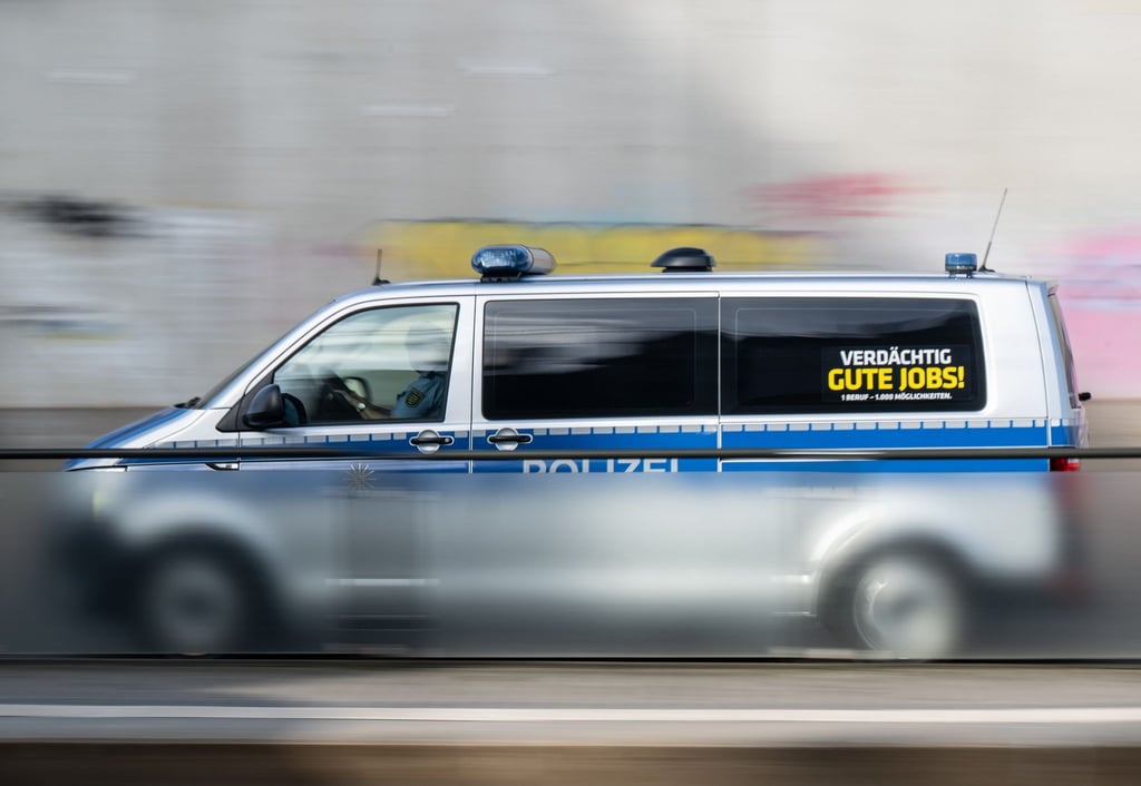 Ein Polizeiauto mit der Aufschrift „Verdächtig gute Jobs!“ fährt eine Straße entlang.