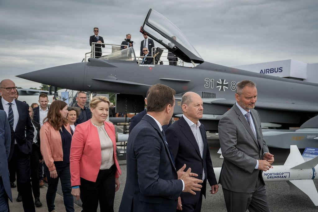 Bundeskanzler Olaf Scholz (SPD,2.v.r) auf der Internationalen Luft- und Raumfahrtausstellung (ILA) vor einem mit einem Taurus-Marschflugkörper bestückten Eurofighter.