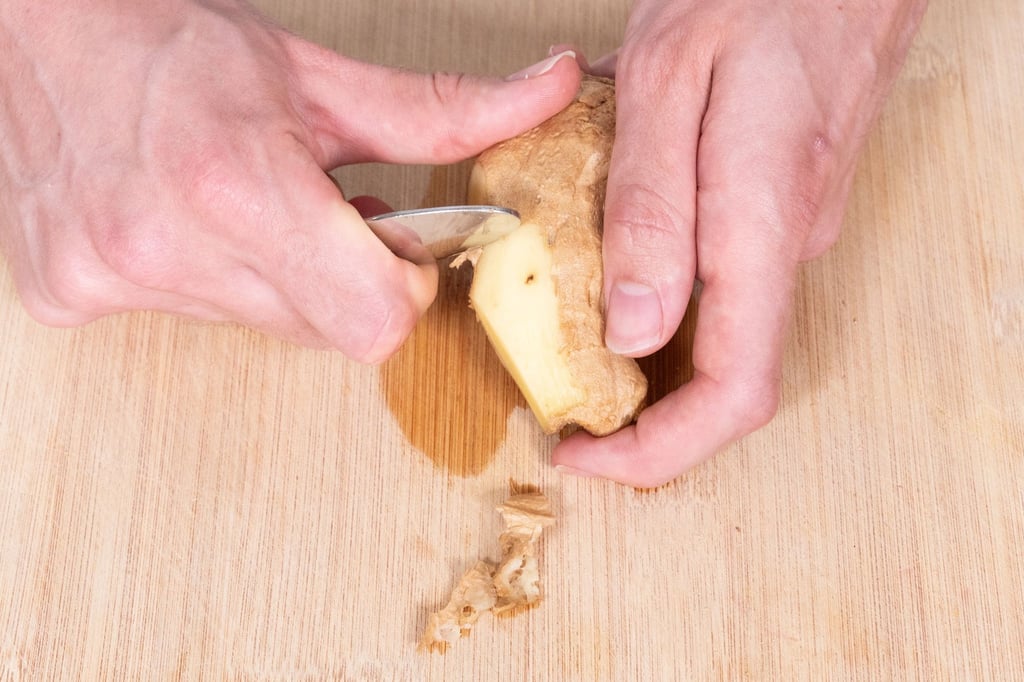 Der Ingwer wird mit der einen Hand festgehalten. In die andere Hand nimmt man die Mulde eines Teelöffels, so dass man mit der Innenseite gut kratzen kann.