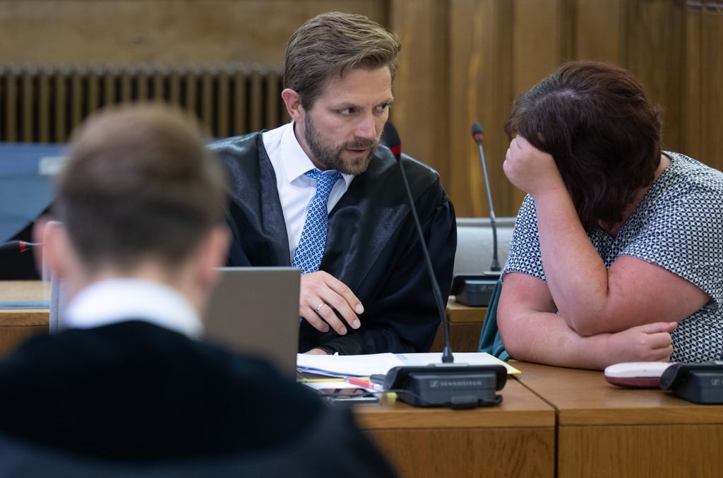 Hinter dem Staatsanwalt unterhalten sich die im sogenannten „Fahrradgate“-Skandal angeklagte Frau und ihr Verteidiger Erik Bergmüller im Landgericht Leipzig.