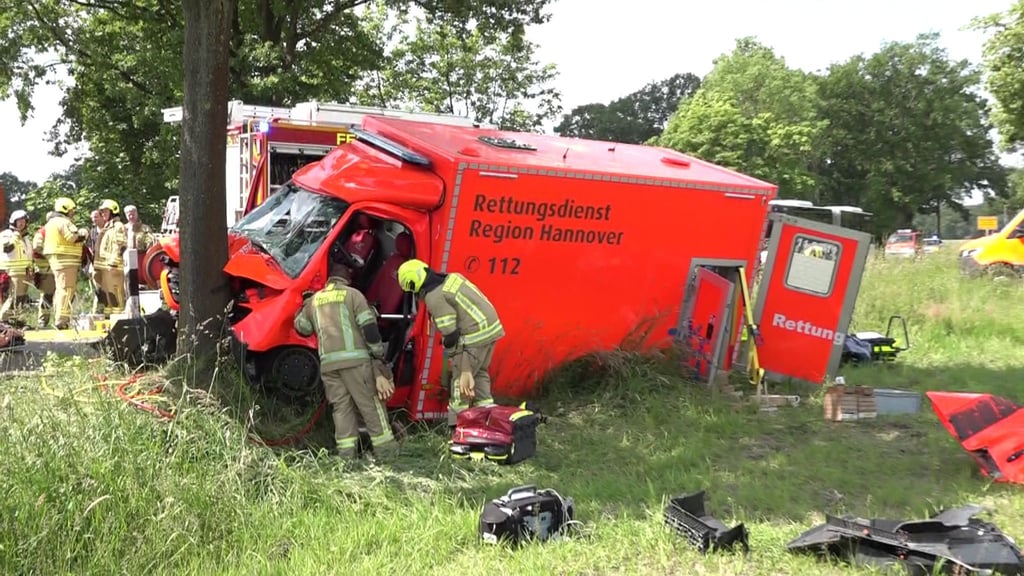 Rettungskräfte stehen neben einem Krankenwagen, der gegen einen Baum geprallt ist.
