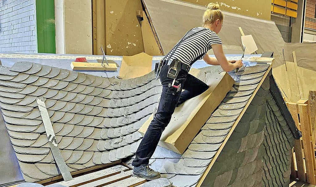 Dinah Metzner bei der Arbeit an ihrem Meisterstück - einer rechten, eingebundenen Schieferkehle auf etwa acht Quadratmetern Fläche. Jede Schieferplatte wird einzeln mit dem Hammer in Form gebracht. Die Arbeit musste in 12 Stunden fertig sein.