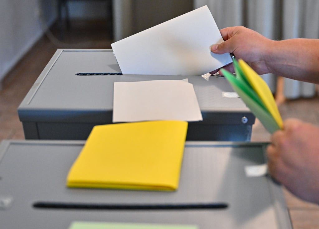 Eine Person steckt seinen Wahlzettel zu Europawahl in eine Wahlurne.