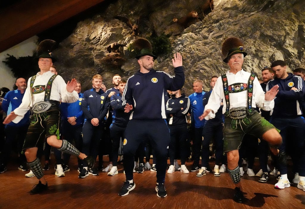 Schottlands John McGinn (M) tanzt mit, als die Mannschaft zu einem Empfang eintrifft.