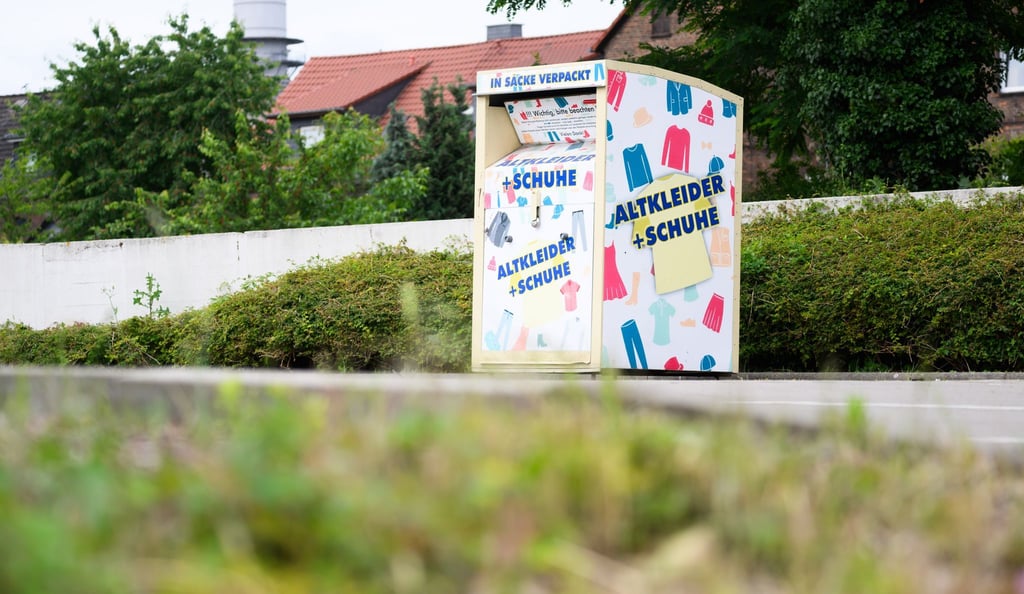 Ein Altkleidercontainer steht auf einem Supermarkt-Parkplatz.
