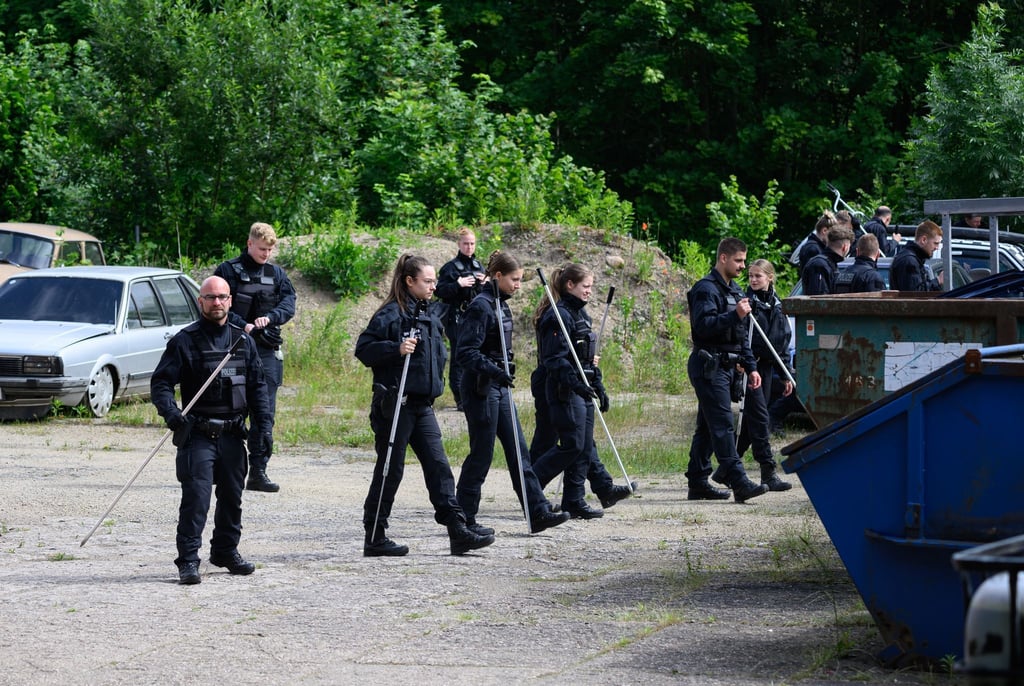 Polizisten sind mit Suchstangen auf der Suche nach einer vermissten Grundschülerin auf einem Firmengelände unterwegs.