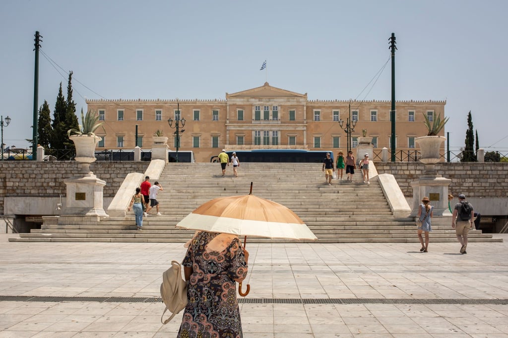 Eine Frau schützt sich mit einem Sonnenschirm auf dem Syntagma-Platz in Athen vor der Sonne: Warme Luftmassen sorgen für Temperaturen von örtlich bis zu 45 Grad.