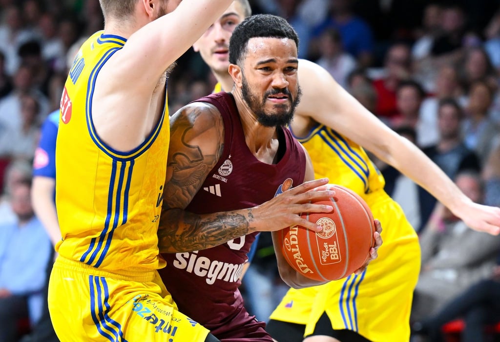 Nick Weiler-Babb (M) von München und Malte Delow (l) von Berlin kämpfen um den Ball.