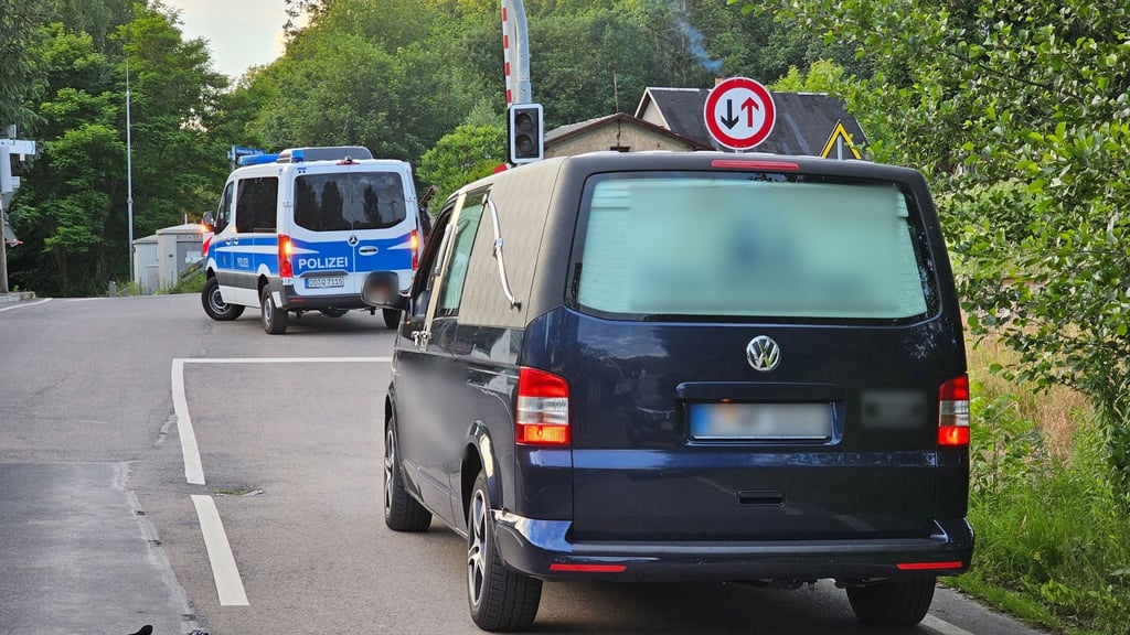 Ein Fahrzeug eines Bestattungsunternehmens fährt hinter einem Fahrzeug der Polizei auf einer Straße.