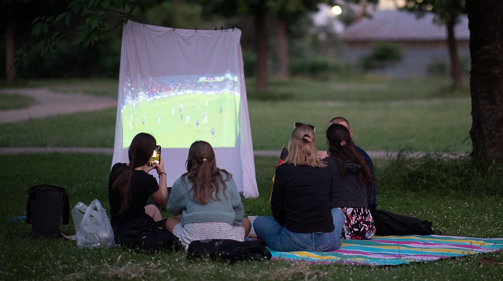 Auch so geht Fußball gucken: Im Park auf einer provisorischen Leinwand, die mit einem Bettlaken gespannt wurde.