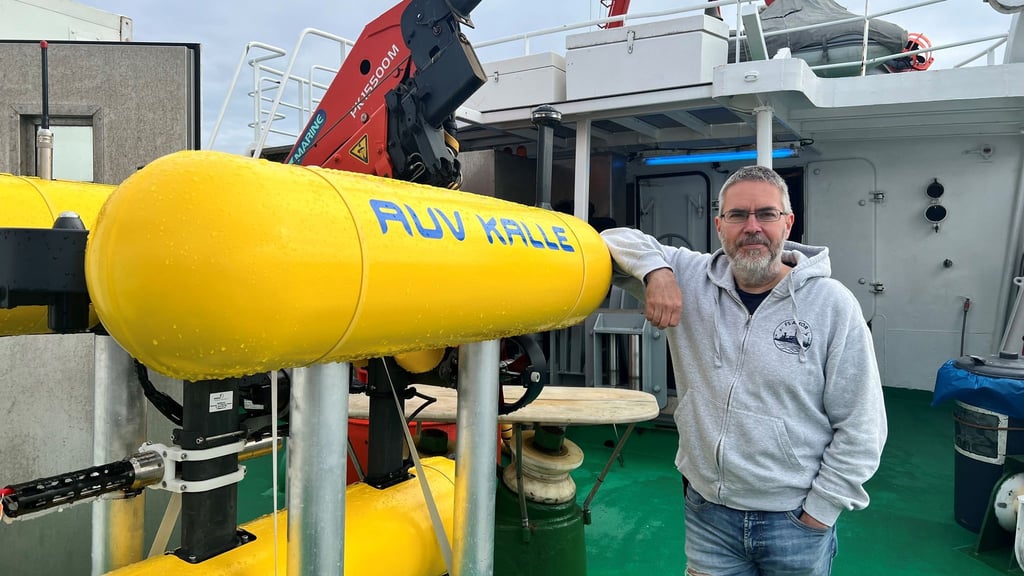 Der marine Geologe Jens Greinert lehnt am autonomen Tauchroboter “Kalle“.