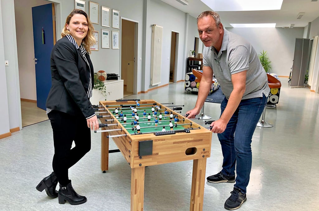 Ziehen gemeinsam an einem Strang: Isabell Wanner und Geschäftsführer Frank Löffler spielen auf dem Flur der Firma Wunds Datensysteme Kicker.