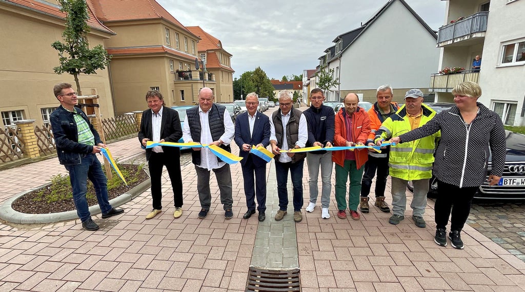 Vertreter der Verwaltung, Projektpartner und Baufirma bei feierlichem Banddurchschnitt zur Freigabe der Schulstraße in Holzweißig.