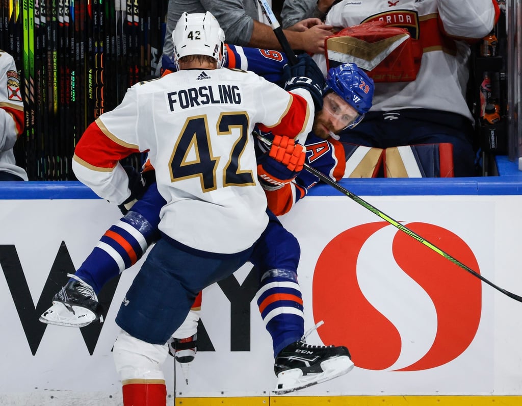 Leon Draisaitl von den Edmonton Oilers wird von Gustav Forsling von den Florida Panthers an die Bande gecheckt.