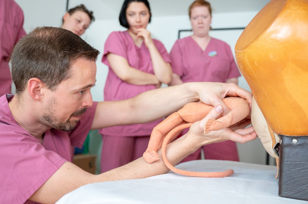 Der Leitende Oberarzt Dr. Marcus Riemer demonstriert den Teilnehmerinnen der Notfallübung in der Uniklinik Halle die Entbindung eines Babys in Beckenendlage am Modell.