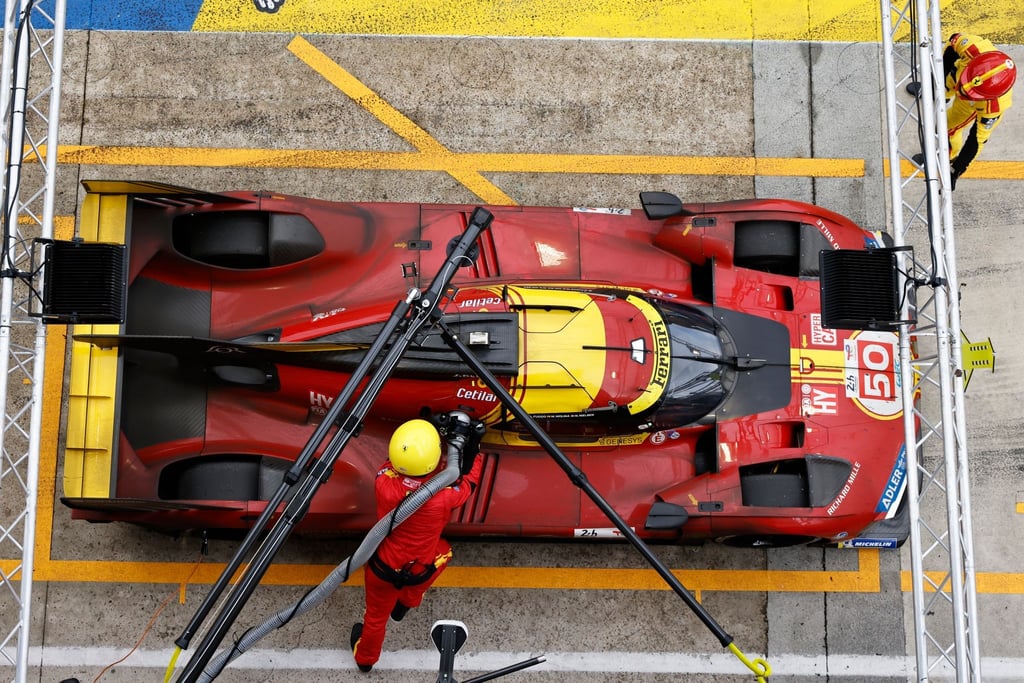 Mechaniker betanken das Auto des Teams Ferrari.