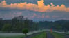 Der Sonnenaufgang scheint auf Wolken über dem Oder-Neiße-Radweg am Deich nahe dem deutsch-polnischen Grenzfluss Oder.