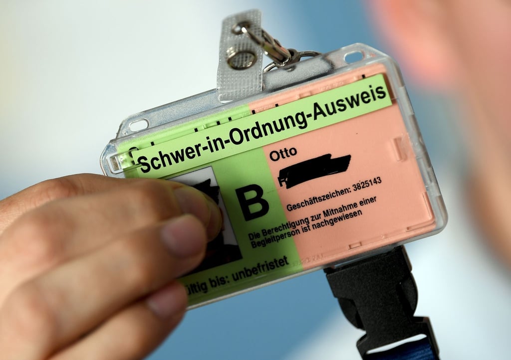 Ein junger Mann zeigt seine neue Hülle für seinen Schwerbehindertenausweis.