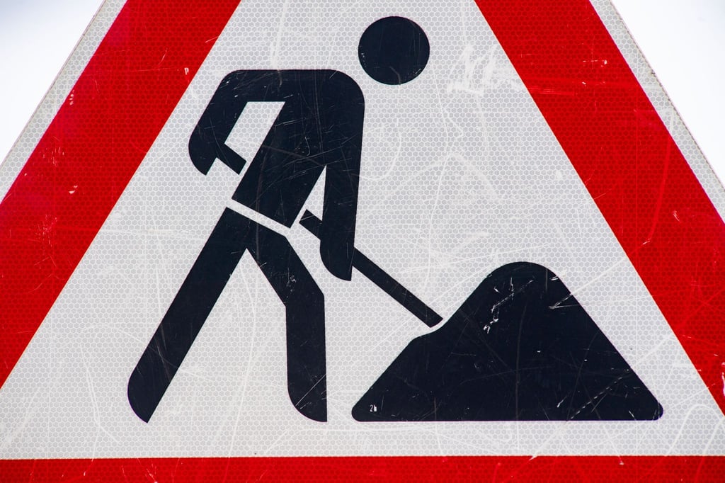 Ein zerkratztes Schild weist auf eine Baustelle hin.