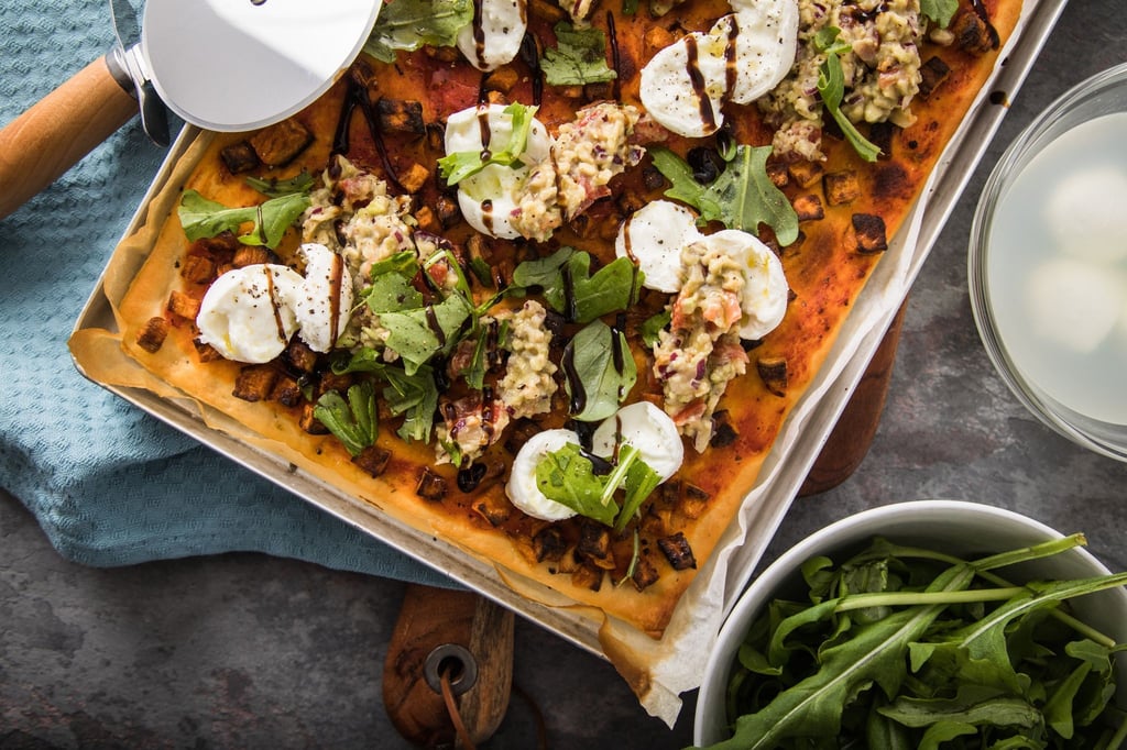 Wie ein Gemälde: Pizza vom Blech mit Süßkartoffel, Büffelmozzarella, Guacamole, Rucola, Balsamico.