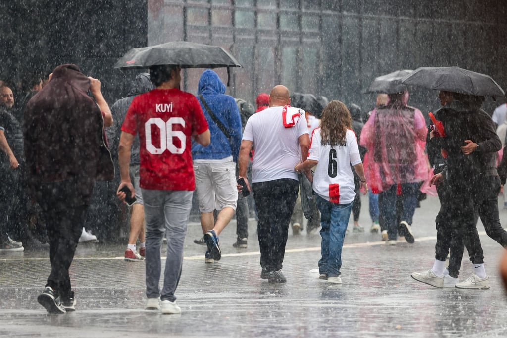 Das haben sie sich sicherlich anders vorgestellt: Fussballfans in Dortmund laufen im strömenden Regen zum Stadion.