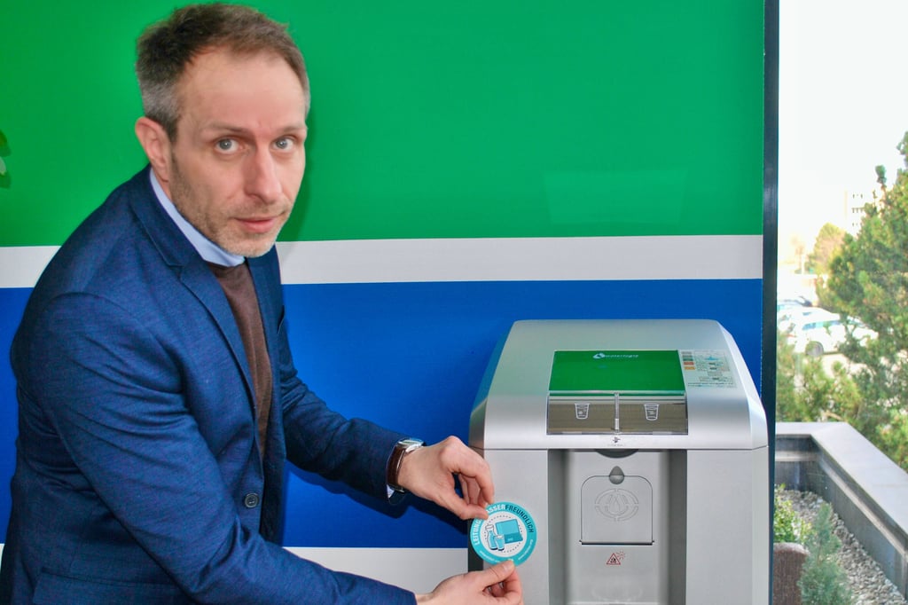Lars Ziemann, Geschäftsführer der Stadtwerke Zeitz GmbH, der hier den Aufkleber „leitungswasserfreundlich“ am Wasserspender im Kundenservice anbringt, setzt auf diesen Hitzeschutz. Dort gibt es nämlich gesundes Leitungswasser für Mitarbeiter und Kunden.