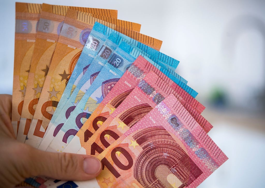 Eine Frau hält Banknoten von 10, 20 und 50 Euro gefächert in der Hand.