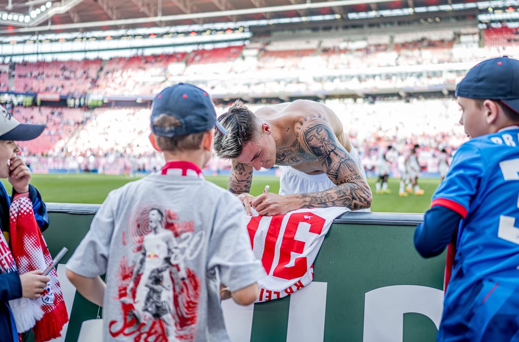 Benjamin Sesko unterschreibt auf einem Trikot.