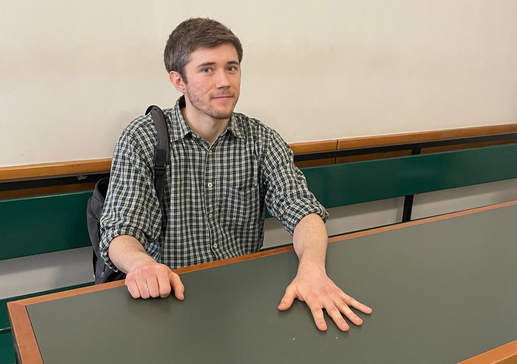 Klimaaktivist Henning Jeschke sitzt festgeklebt an einem Tisch in einem Raum des Amtsgericht Tiergarten.