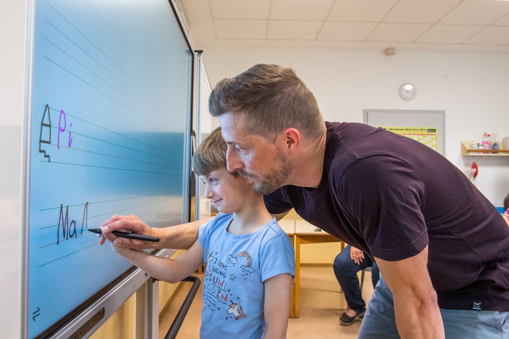 Anna, 2. Klasse, aus der Käthe-Kruse-Schule in Naumburg übt mit Lehrer Thomas Töpleb das Schreiben an der digitalen Tafel.