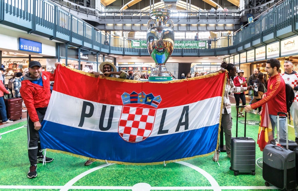 Kroatische Fußballfans posieren im Hamburger Hauptbahnhof mit ihrer Fahne.