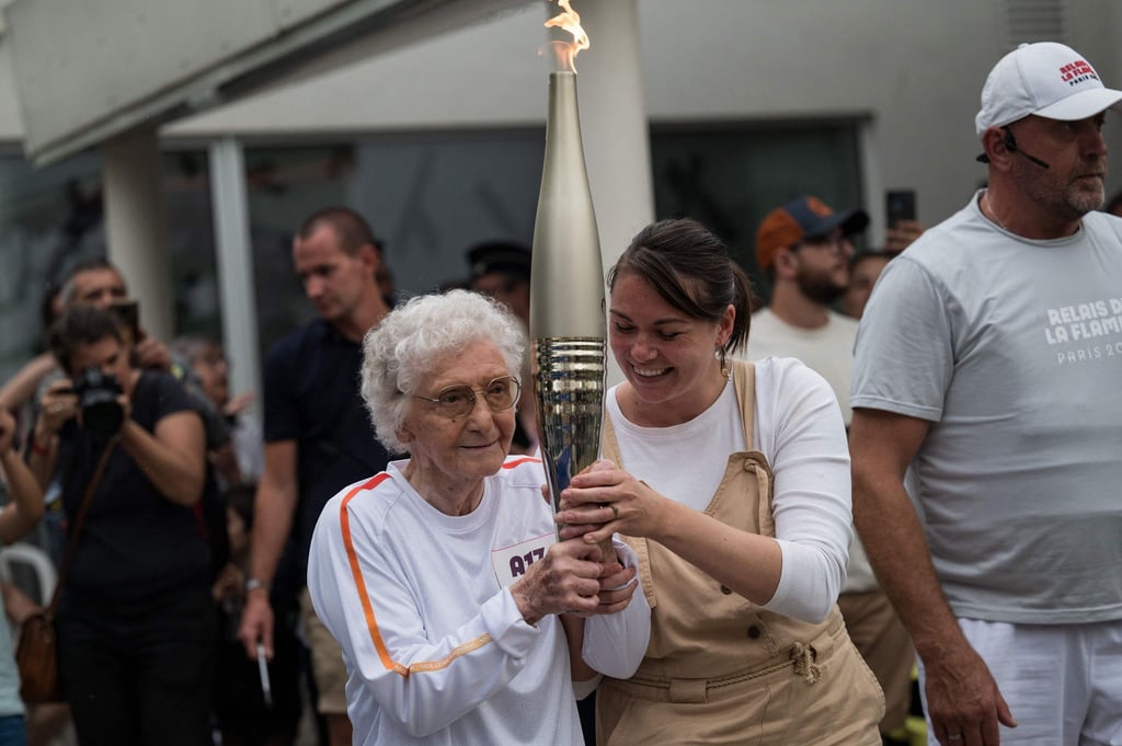 Melanie Berger-Volle (M) hält in einem Seniorenheim in Saint-Etienne die olympische Fackel.
