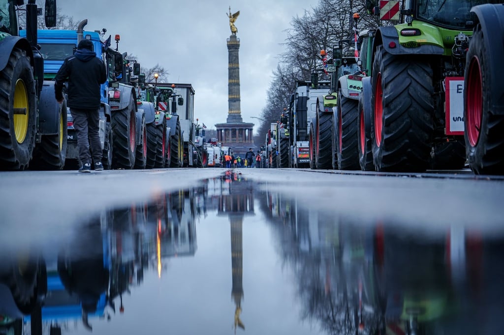 Die Siegessäule und Traktoren spiegeln sich in einer großen Pfütze.