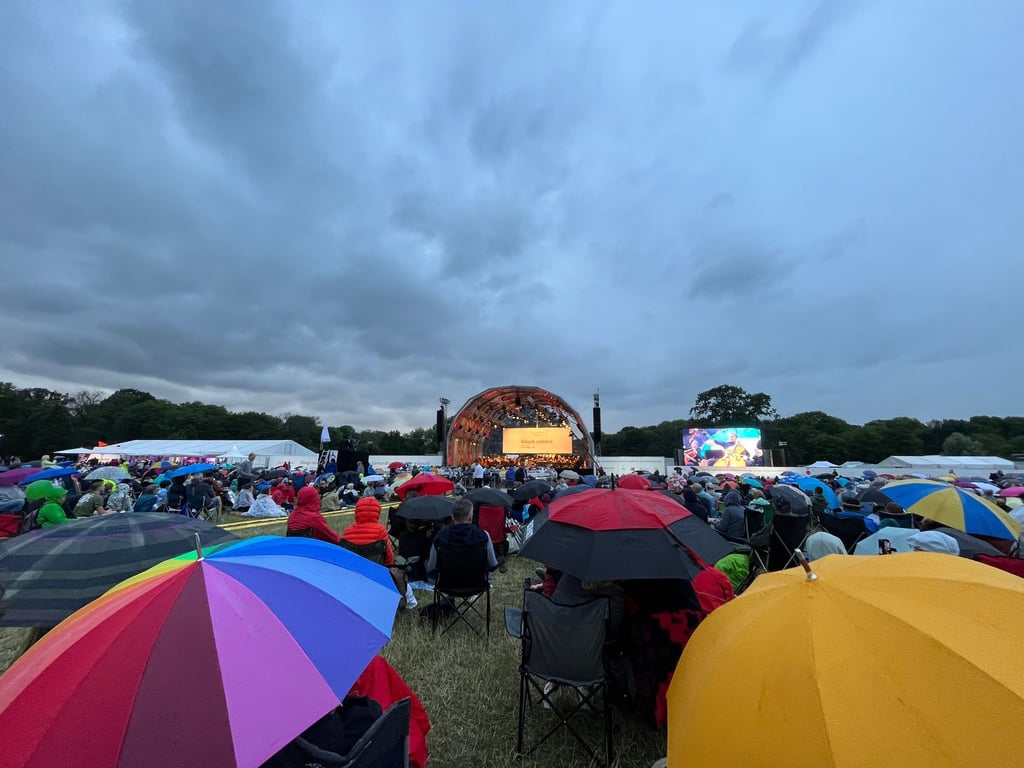 Tausende Besucher sitzen mit Regenschirmen im Rosenthal und hören einem Open-Air Konzert des Leipziger Gewandhausorchesters zu.