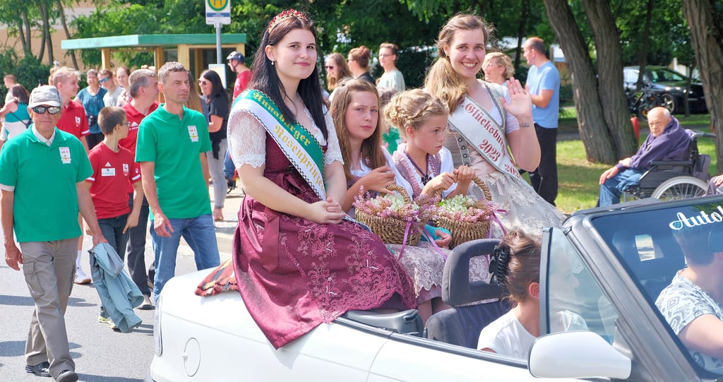 Rosenprinzessin Paula Mikosch und Heidekönigin Patricia Schulze winken den Zuschauern vom offenen Cabrio aus zu.