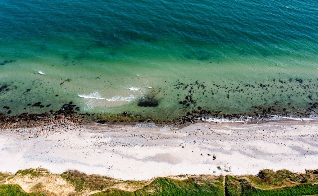 Wellen laufen am Strand der Ostsee am sogenannten Schwedeneck auf den Sand.