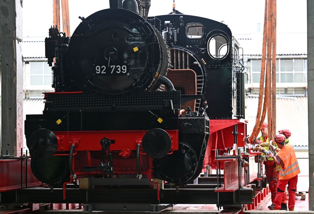 Eine preußische T13 Dampflokomotive wird mit dem Spezialkran in eine Gebäudeöffnung gehoben.