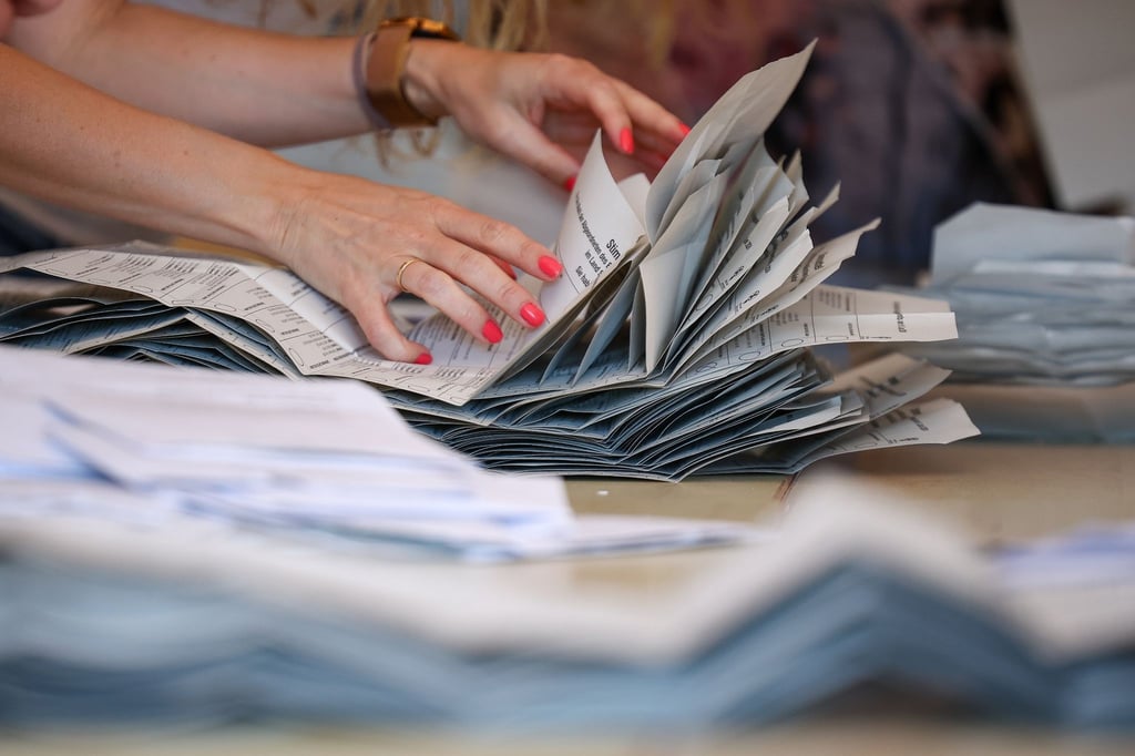 Eine Wahlhelferin legt Stimmzettel zur Stimmenauszählung der Briefwahlstimmen zur Europawahl auf einem Stapel.