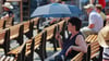 Mit einem Schirm sitzt eine Frau in Wernigerode auf einer Bank.