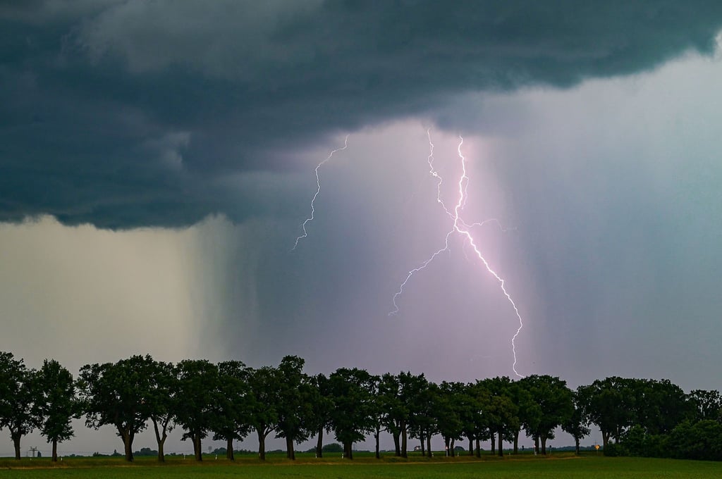 Ein Blitz leuchtet am späten Abend über der Landschaft.