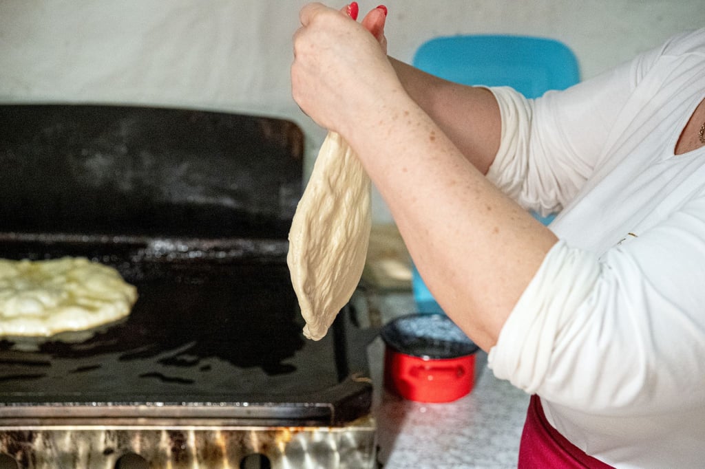 Aus der faustgroßen Teigkugel wird der Teig für den Lángos mit der Hand auf Tellergröße platt gestrichen.