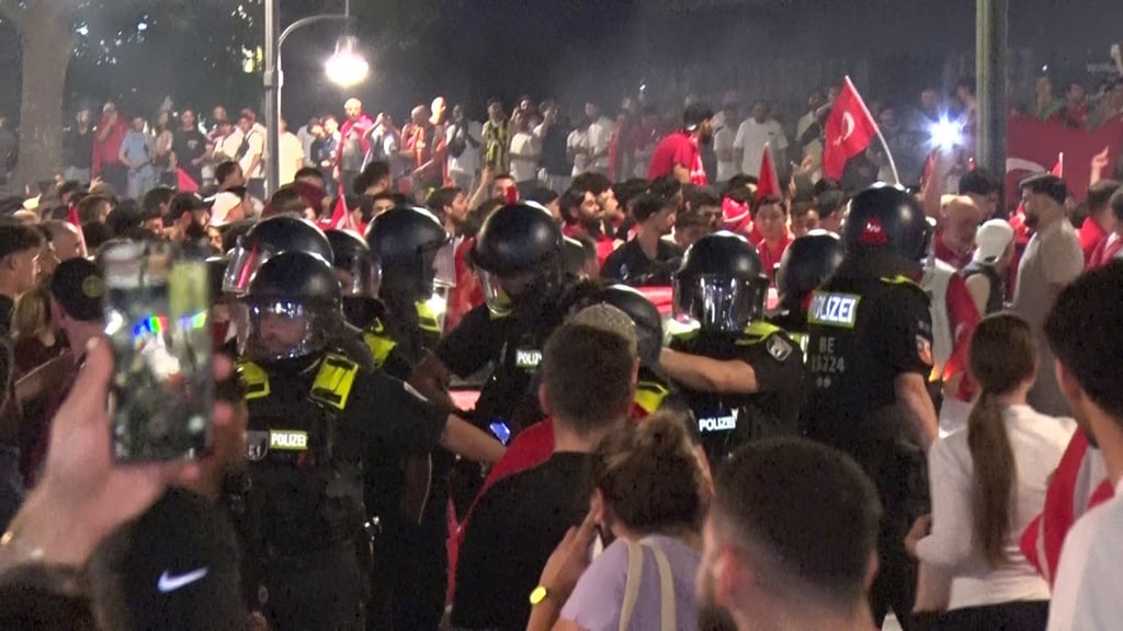 Fans der Türkei feiern den Sieg ihrer Mannschaft, während die Polizei im Einsatz ist.