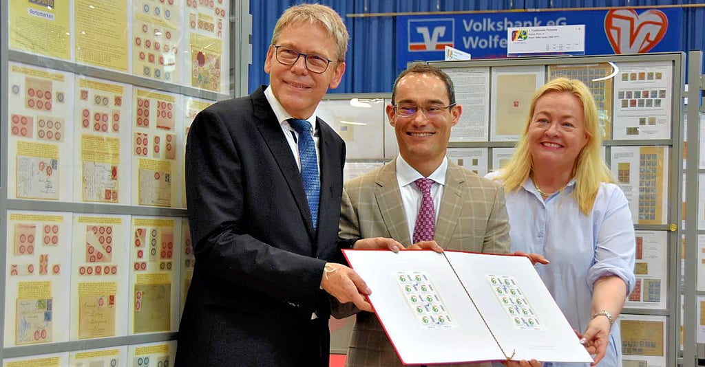 Alfred Schmidt (v.l.), Präsident des Bundes Deutscher Philatelisten, Luiz Eduardo Concalves, Gesandter der brasilianischen Botschaft, und Daniela Zehentner-Capell, Referatsleiterin für Münzen und Postwertzeichen im Bundesministerium der Finanzen, präsentieren die neuen Briefmarken zum Jubiläum.