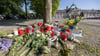 Blumen, Kerzen und handgeschriebene Trauerbekundungen stehen an einem Baum im Kurpark Bad Oeynhausen.