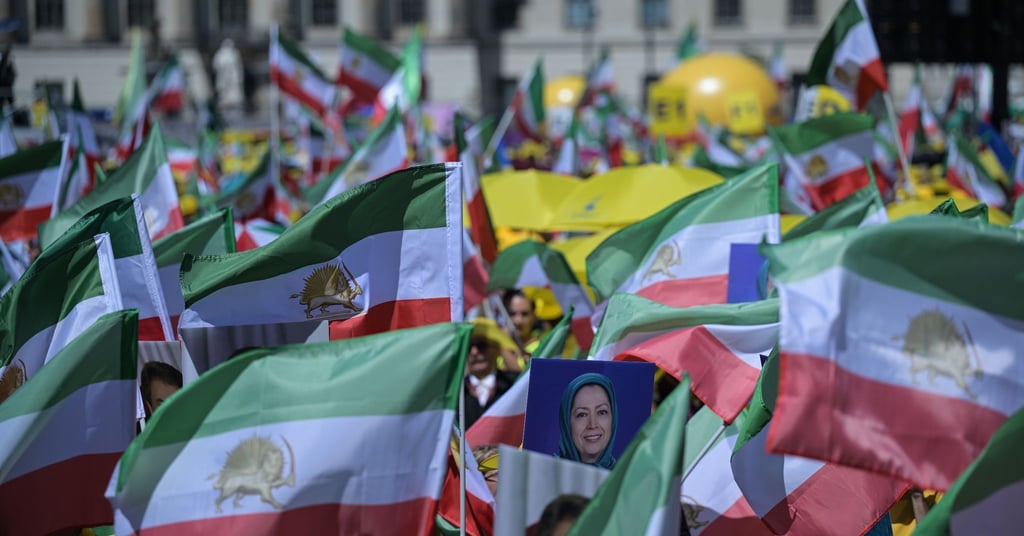 Teilnehmer der Kundgebung schwenken iranische Flaggen.