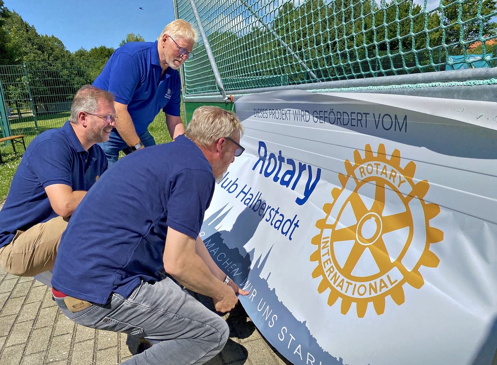 Christian Dreyer (vorn), Andy Hänsler und Rainer Knackstedt (hinten) vom Rotary Club Halberstadt bringen die Bandenwerbung des Clubs am Mini-Fußball-Felds im Nordring Halberstadt an.