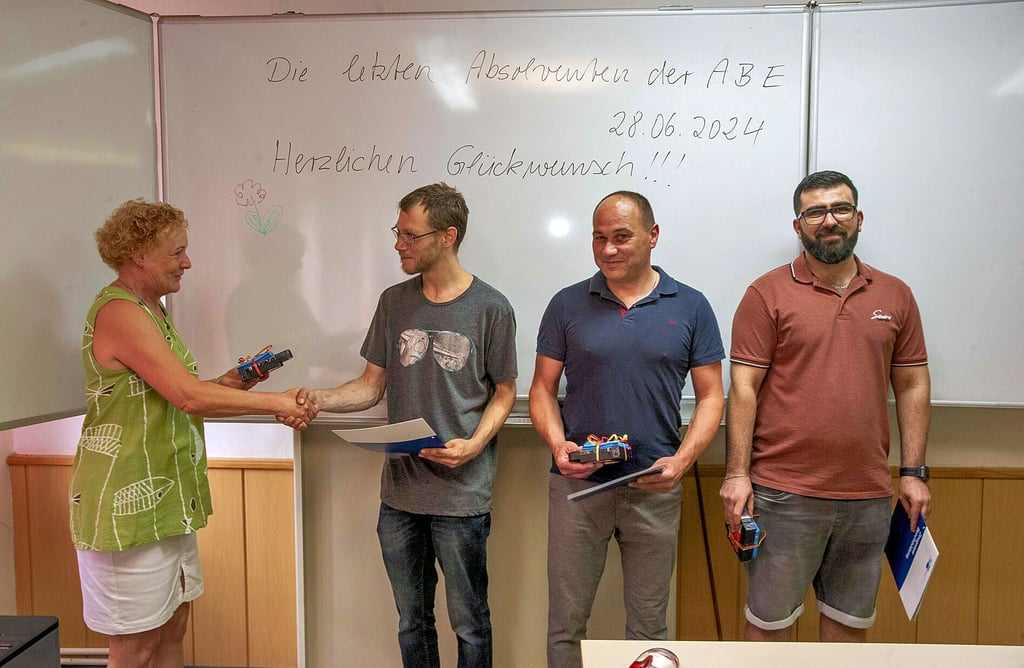 Monika Gehrbrandt vom Bildungsträger ABE gratuliert Daniel Hielscher, Mario Zunder und Goran Mustafa (v.l.n.r.) zum erfolgreichen Abschluss ihrer Umschulung zum Industrieelektriker. Die drei sind die letzten Teilnehmer von ABE.