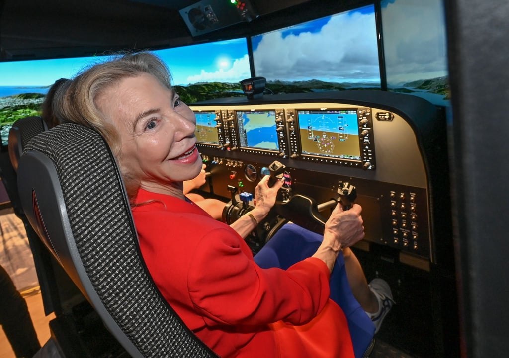 US-Botschafterin Amy Gutmann testet die Newton Flight Academy und sitzt am Simulator.